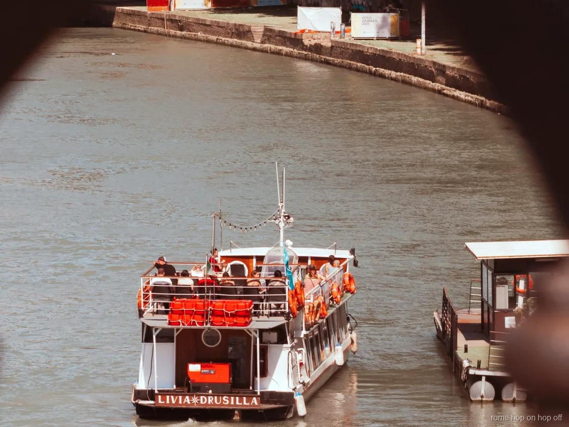 Battello hop on hop off Roma sul Tevere sotto un ponte storico