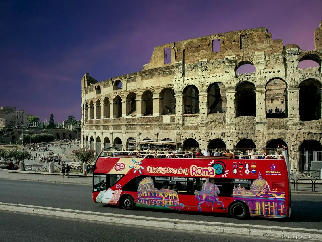 Rome hop-on hop-off night bus tour passing the illuminated Colosseum