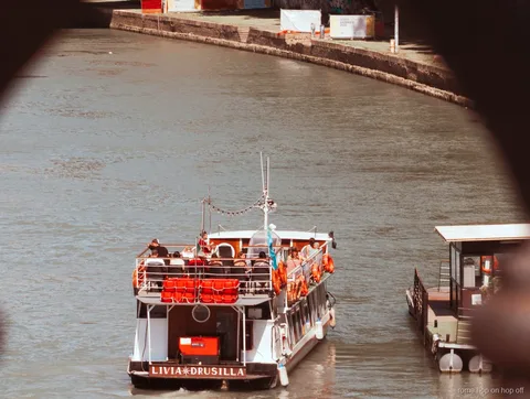 Rome Tiber River hop-on hop-off boat passing beneath a historic bridge